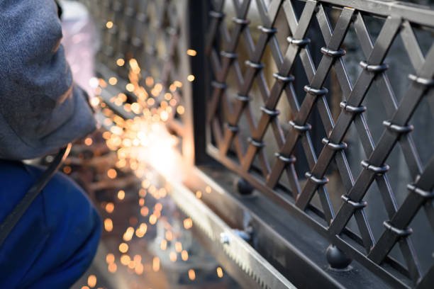 A man skillfully welding metal components on a fence, showcasing precision and craftsmanship in fence and gate maintenance in Santa Monica.