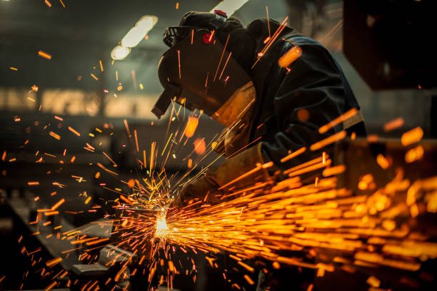 A man welding in a factory, surrounded by flying sparks, showcasing the intensity of industrial craftsmanship in metal and gates repair in Orange County.