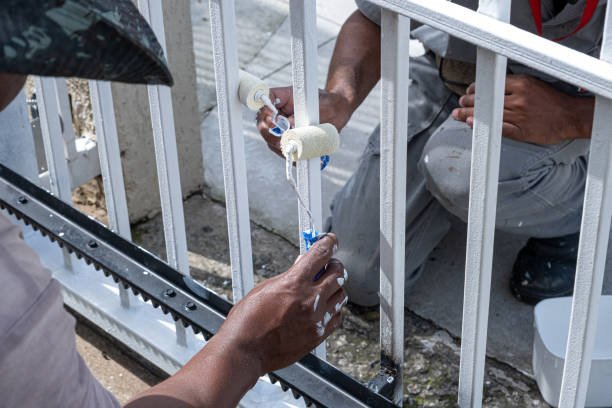 Two painters working on the electric gate of a condominium, showcasing expert garage door repair and painting services in Pasadena.