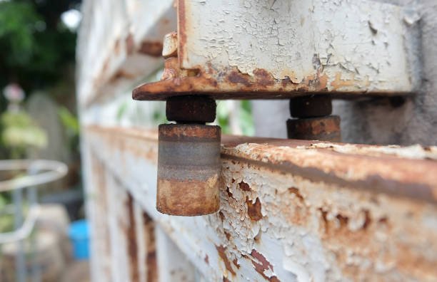 A close-up of rusty metal bolts affixed to a weathered iron door, showcasing signs of age, corrosion, and the need for iron door repair.