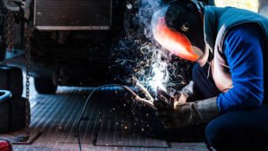 A certified welder in Los Angeles focused on custom metal fabrication, with bright sparks reflecting off his helmet in a workshop.