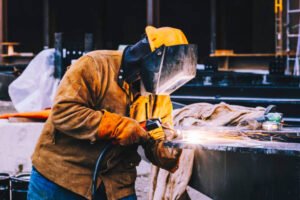 A welder wearing a helmet focused on custom metal fabrication in a Los Angeles workshop