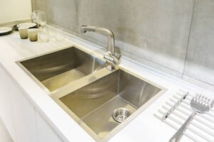 A stylish kitchen with a stainless steel sink and counter, highlighting a modern aesthetic and functional layout featuring a premium stainless steel sink.
